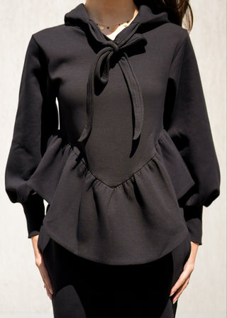 Black peplum top worn by a person on a plain background
