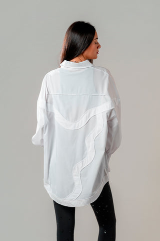 Person wearing a white oversized shirt with black pants on a plain background